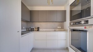 Una cocina moderna con armarios grises, horno integrado y encimera con hervidor y tostadora.