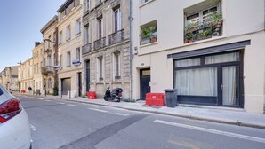 Une vue de rue avec une rangée de bâtiments, une voiture garée et un scooter.