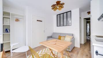 A modern kitchen with white cabinets, a wooden table, and a yellow chair.