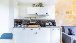 A compact kitchen with white cabinets, a black tiled backsplash, a built-in stove, and a small countertop.