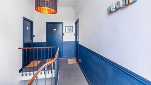 A hallway with a staircase, a hanging light fixture, and a sign that reads "Welcome".