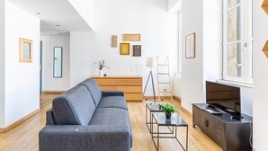 A modern living room with a grey sofa, a small table with a plant, a TV on a cabinet, and a ladder against the wall. - Beautiful apartment with Parking at Bordeaux (Bordeaux)