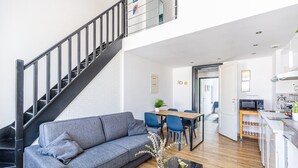 A modern apartment with a grey sofa, a dining area, a kitchen, and a staircase. - Beautiful apartment Bordeaux center (Bordeaux)