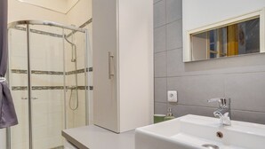 A modern bathroom with a glass-enclosed shower, a white sink, and a mirror above it.