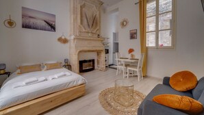 A bedroom with a bed, a fireplace, a dining area, and a sofa.
