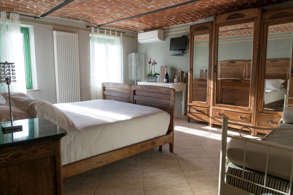 A bedroom with a bed, wooden dresser, and a desk with a lamp.