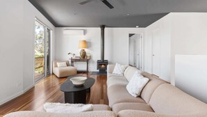 A modern living room with a sofa, a coffee table, a fireplace, and a ceiling fan.