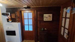 Interior de madeira com uma porta, uma mesa pequena com um vaso e um quadro na parede.