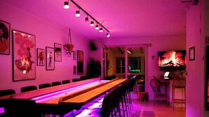 A long communal table with chairs, a television, and framed artwork on the walls. - Amsterdam Villa | Jacuzzi, Sauna & Cinema (Zwanenburg)