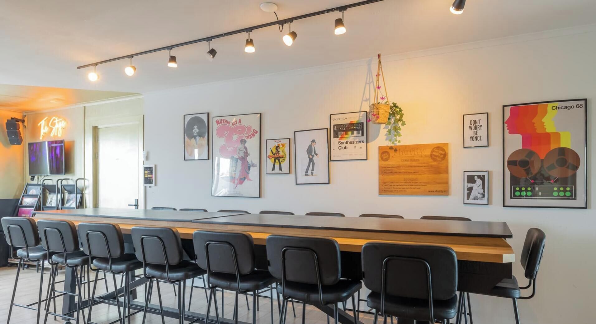 Un salón de conferencias con una larga mesa y sillas, obras de arte colgadas en la pared y una pantalla de televisión.