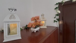A wooden table with two white lanterns and a potted plant with pink flowers. - I Cappuccini B&B (Sorso)