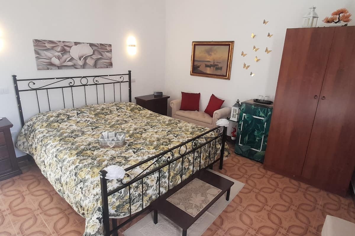 A bedroom with a bed, bedside table, dresser, and a wardrobe.