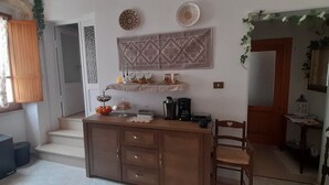 A compact kitchen with a wooden island, a coffee maker, and decorative items on the wall. - I Cappuccini B&B (Sorso)