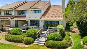 Una casa moderna a due piani con tetto in tegole, ampie finestre e un giardino curato.