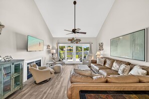 A spacious living room with a large sofa, a fireplace, a ceiling fan, and a view through the glass doors. - Golf Cart ~ End Unit with Loft ~ Master Balcony (Miramar Beach)