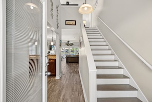 Un escalier avec des rampes blanches et des marches en bois menant à un palier situé au deuxième étage.