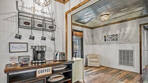 Ein Bereich mit einer Kaffeebar, einer Kaffeemaschine, einem Schild mit der Aufschrift 'COFFEE' und einem an der Wand befestigten Schild, das 'Kaffeebar' zeigt.