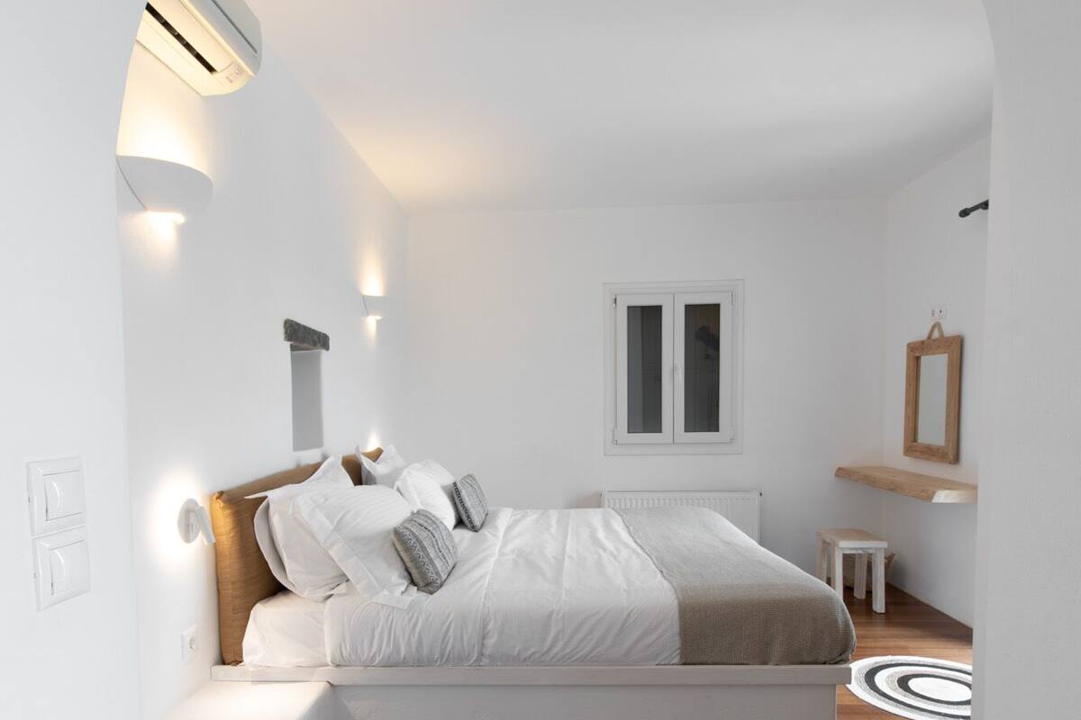 Ein Schlafzimmer mit integriertem Bett, weißen Wänden, Holzboden, einem kleinen Tisch und einem Spiegel.