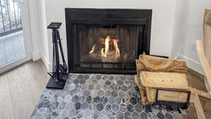 A fireplace with a stone-patterned floor, a TV mounted above it displaying a mountain landscape, and a tripod stand to the left.