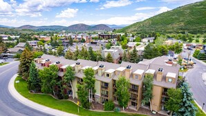 A multi-story residential building with a central courtyard, surrounded by greenery and a curved road.