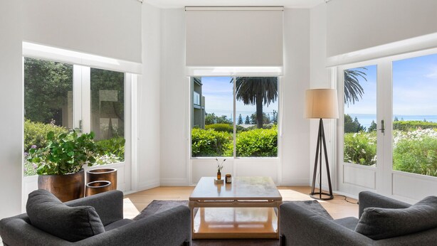A modern living room with a large window, a coffee table, and two sofas.