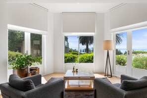 A modern living room with a large window, a coffee table, and two sofas.