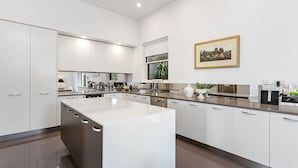 A modern kitchen with white cabinetry, a central island, and a dining area.