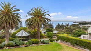 A coastal residential area with palm trees, a gazebo, and a view of the ocean.