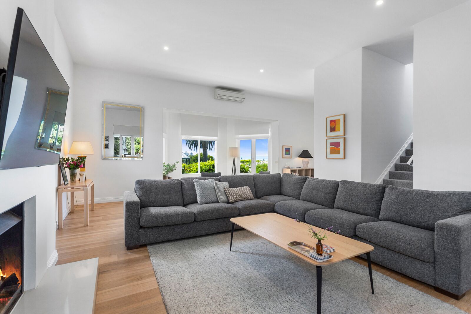 A modern living room with a grey sectional sofa, a wooden coffee table, and a fireplace.