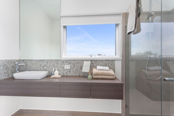 A modern bathroom with a large window, a vessel sink, and a shower area.