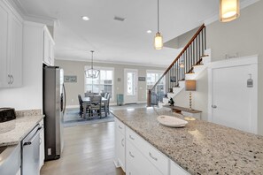 A modern kitchen with granite countertops, stainless steel appliances, and a dining area with a wooden table and chairs.