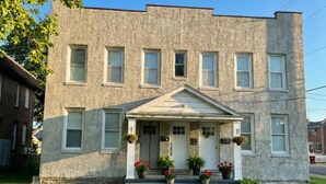 A two-story building with a symmetrical facade, a central entrance with a small porch, and a number "155" on the front. - Newly Renovated Apt with King Bed (Wilmington)