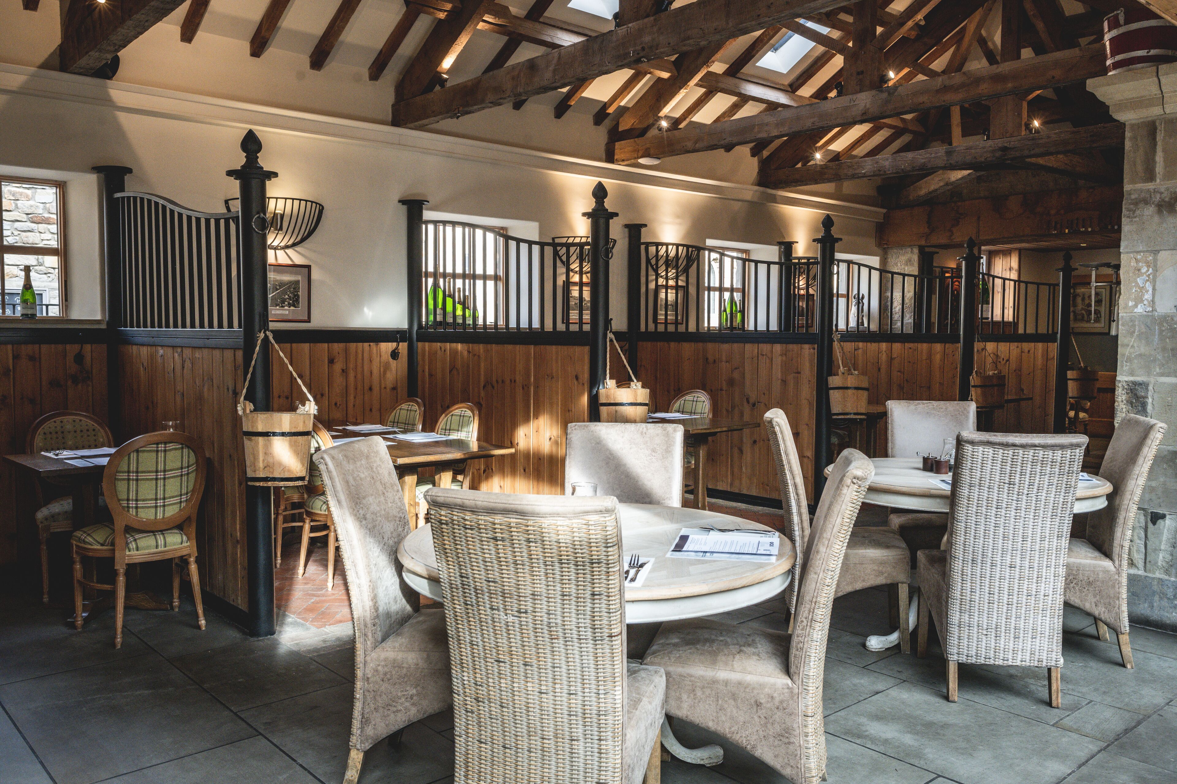 A restaurant with wooden walls, wicker chairs, and a high ceiling with exposed beams.