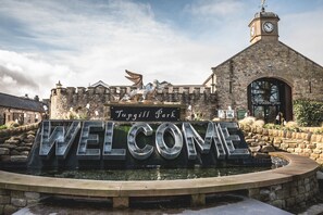 A stone building with a clock tower and a sign that reads "Welcome to Tuppgill Park." - The Saddle Room Restaurant (Leyburn)