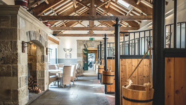A stone fireplace, wooden barrels, and a wooden staircase in a rustic interior. - The Saddle Room Restaurant (Leyburn)