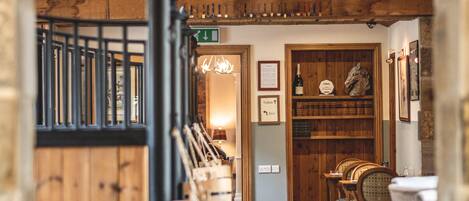 An interior with a wooden archway leading to a dining area with wooden furniture and a wine rack.