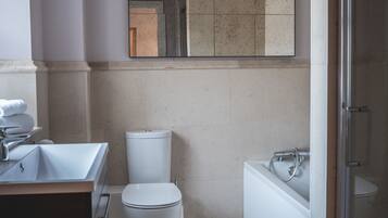 Uma casa de banho moderna com uma pia, sanita e banheira brancas.