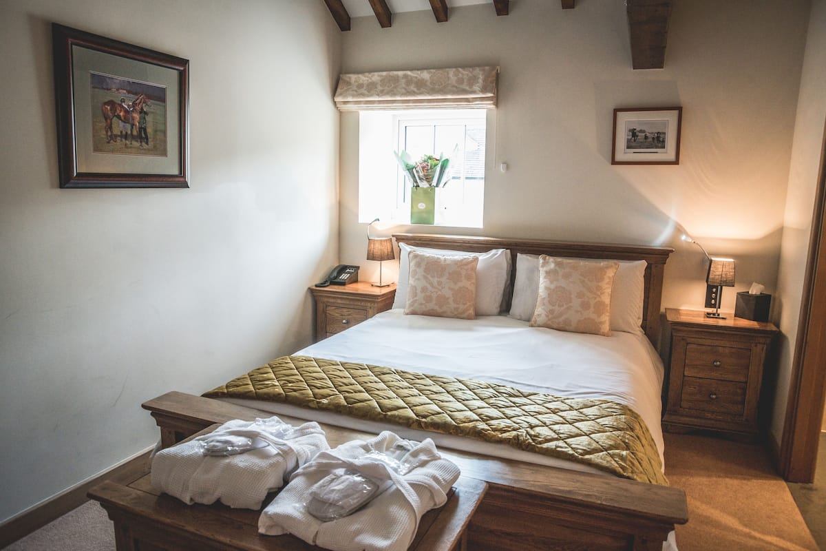 Un dormitorio con cama, mesitas de noche, ventana con vistas y un cuadro en la pared.