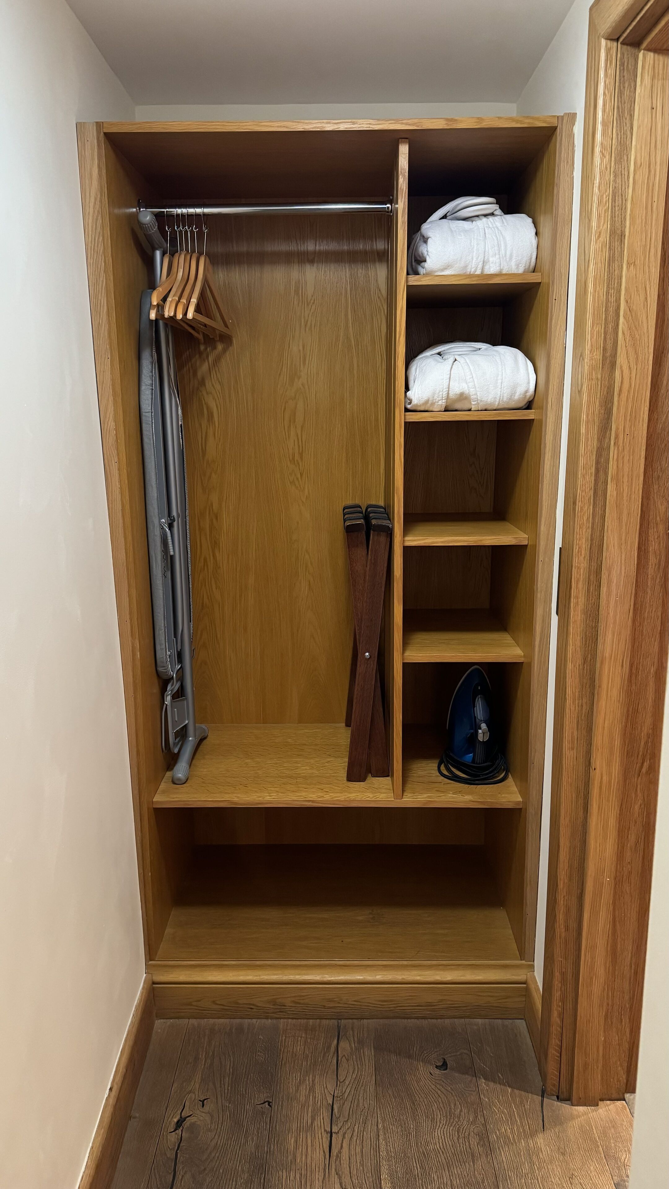 A wooden closet with shelves, a hanging rack, and a shoe rack.