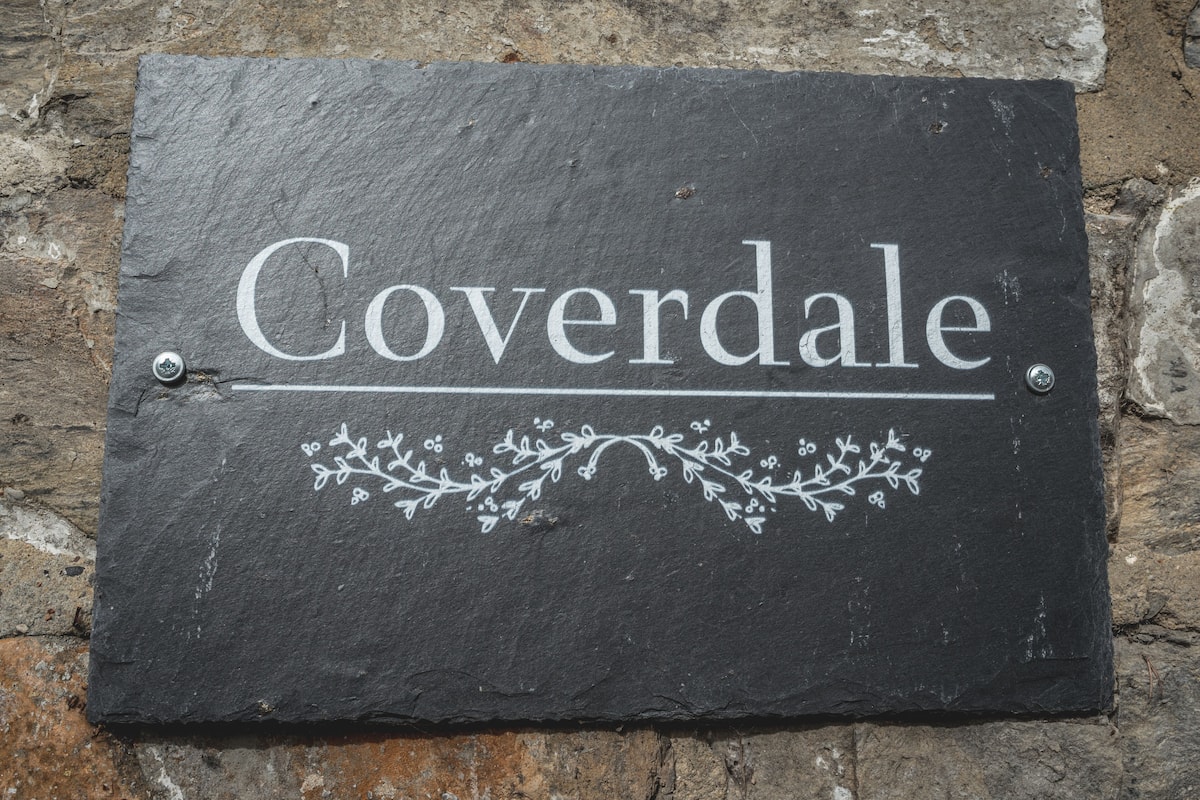 Un letrero de pizarra con la palabra 'Coverdale' y motivos florales decorativos.