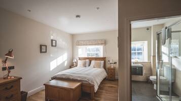 A bedroom with a wooden bed, bedside tables, a desk, and a window.