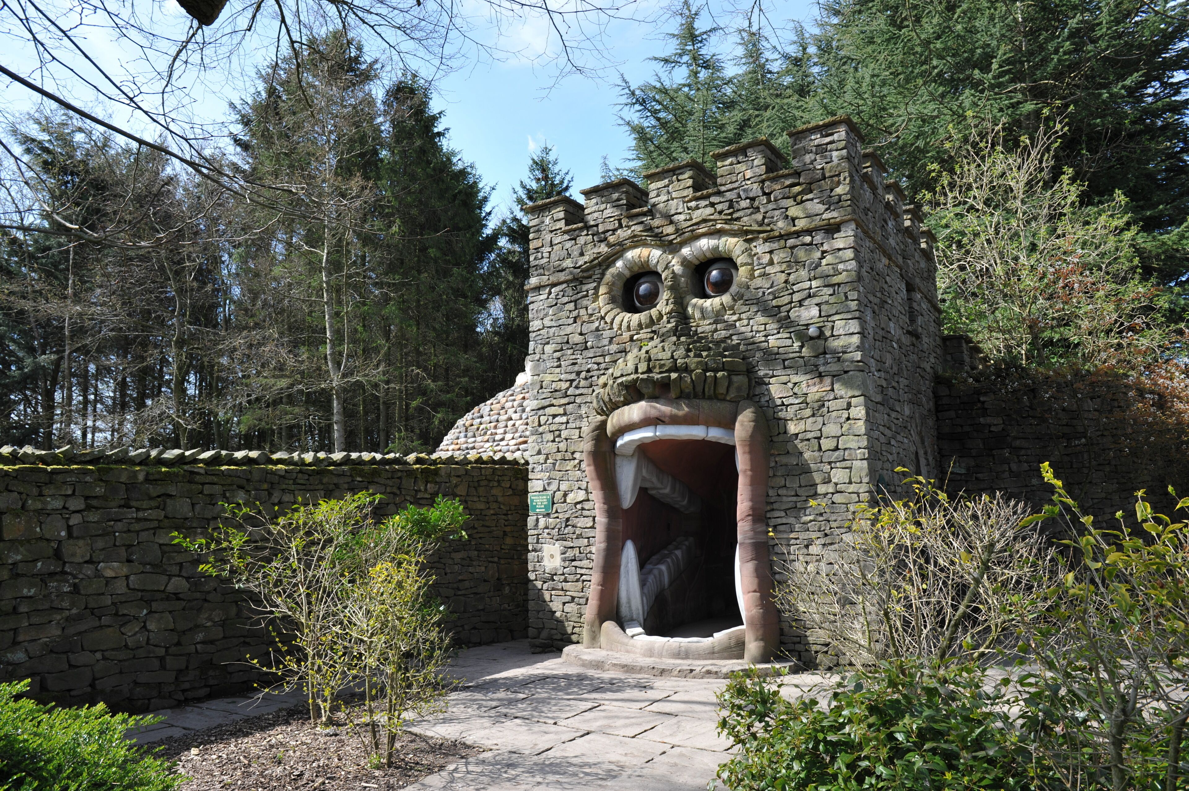 Un edificio de piedra con una gran abertura en forma de boca y dos ojos grandes, rodeado de árboles.