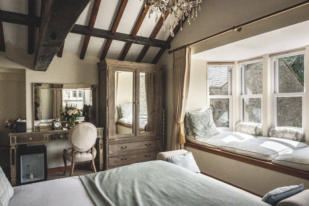 Un dormitorio con una cama grande, un aparador, una silla y una ventana con vistas al exterior.