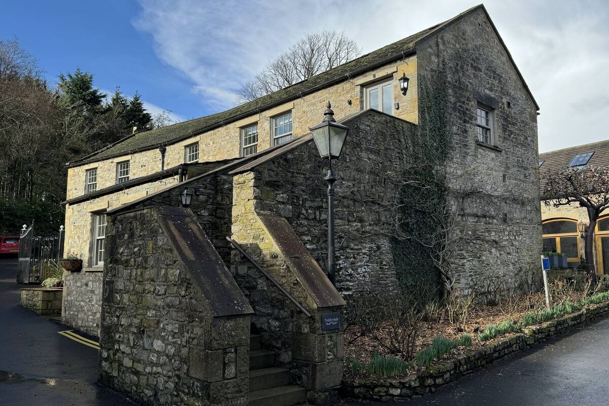 Un edificio de piedra con una escalera que conduce a la entrada, un cartel que dice