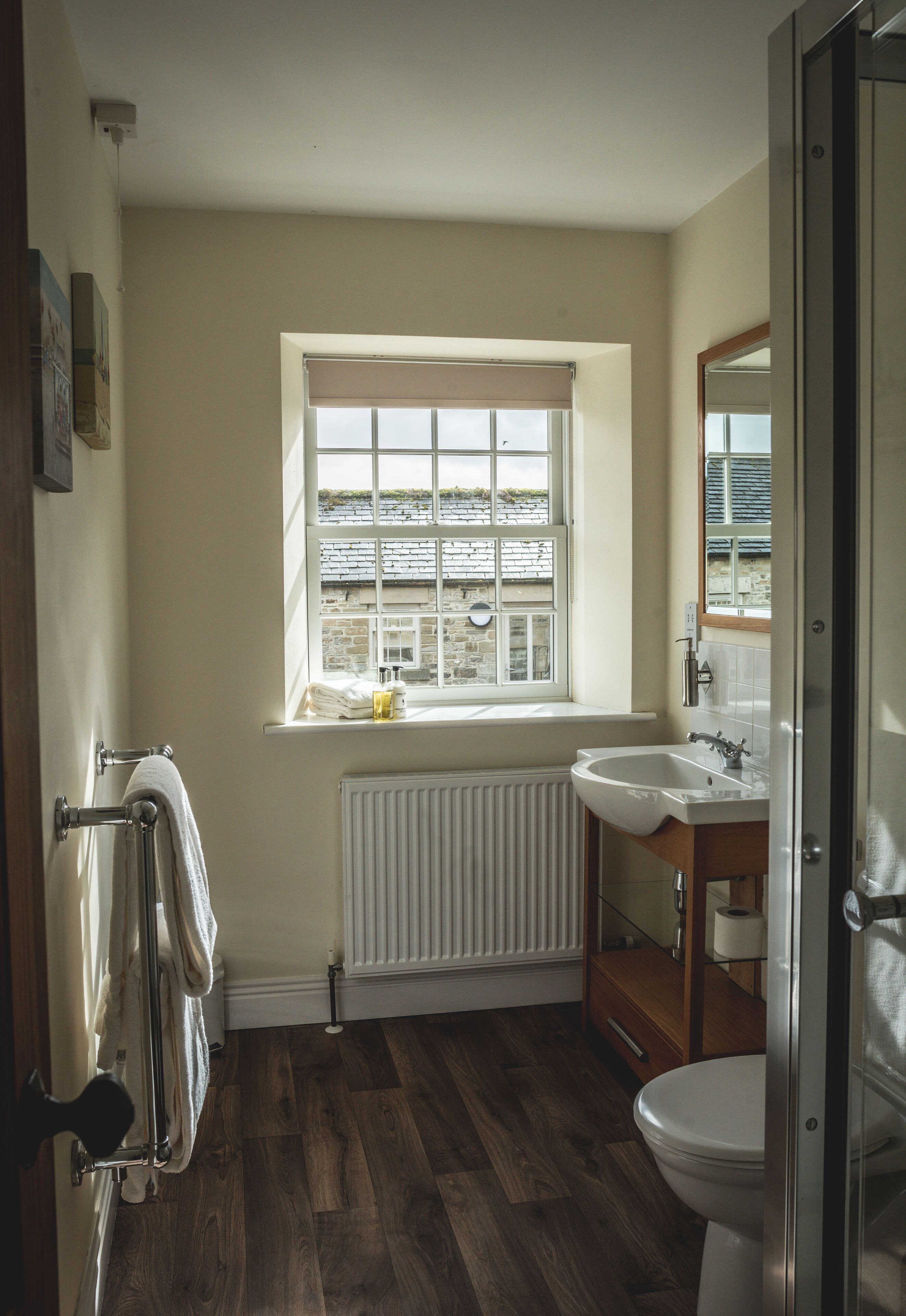 Un baño con ventana, radiador, lavabo e inodoro.