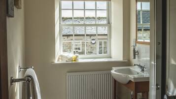 Un baño con ventana, radiador, lavabo e inodoro.
