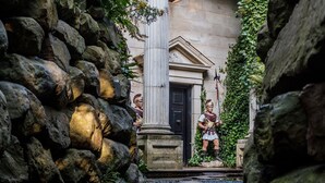 A stone pathway leading to a classical building with a statue of a warrior. - The Saddle Room Restaurant (Leyburn)
