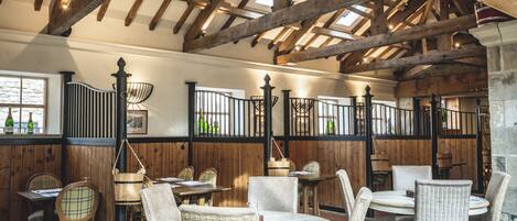 Un restaurante con vigas de madera, sillas de mimbre y mesas.
