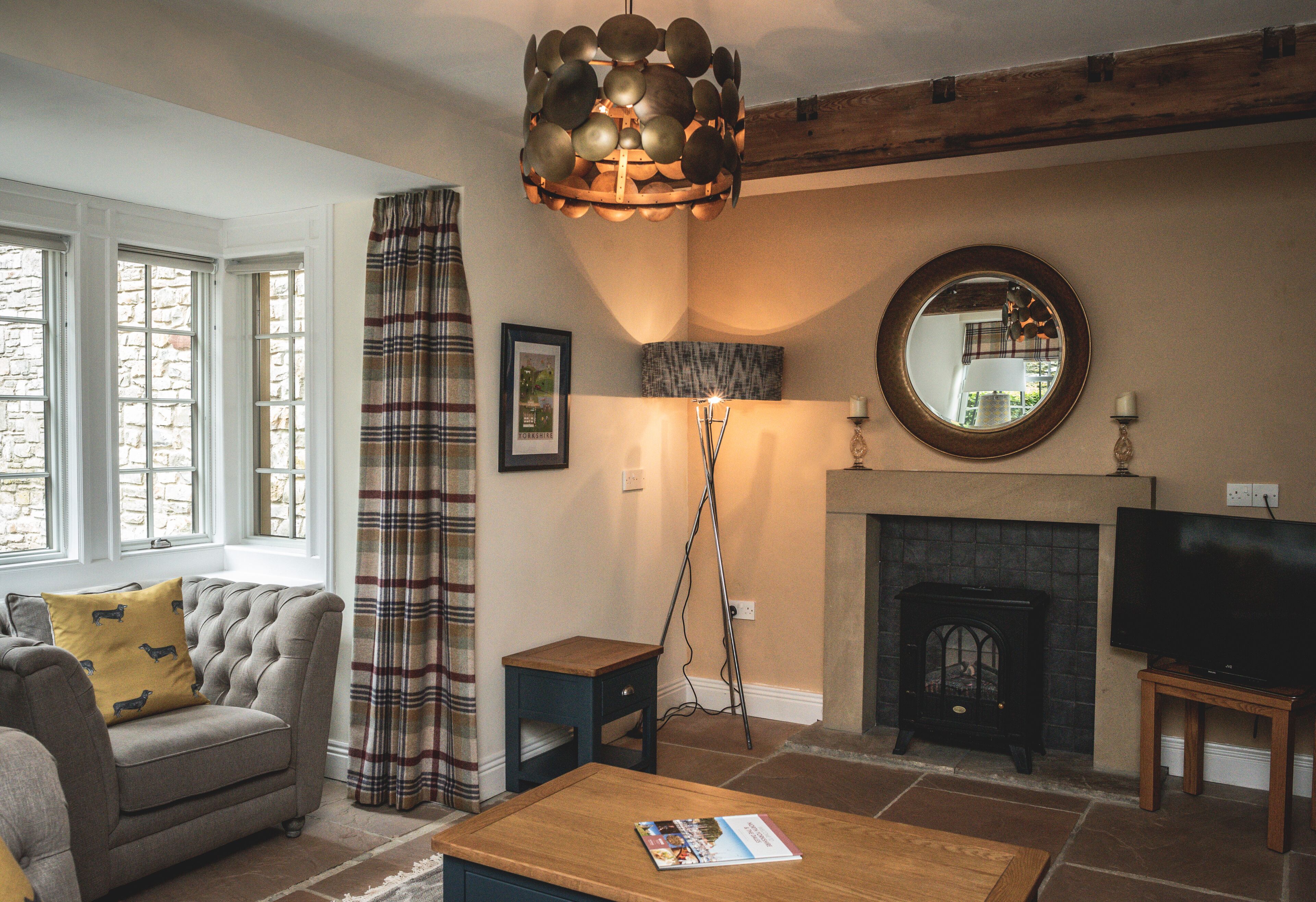 Una sala de estar con chimenea, televisor y sofá con cojines estampados.