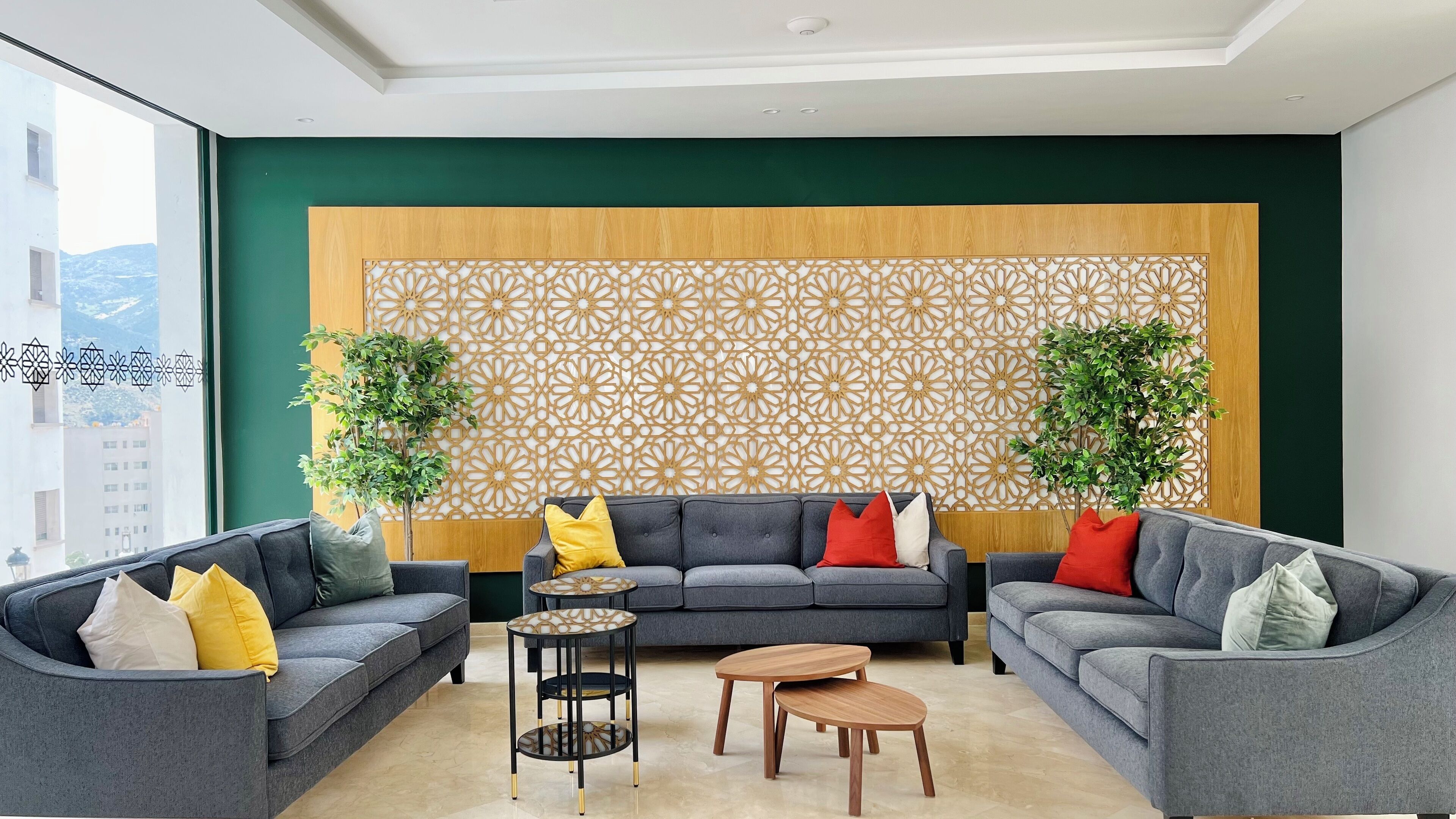A modern living room with two grey sofas, a wooden coffee table, and a patterned wall divider.